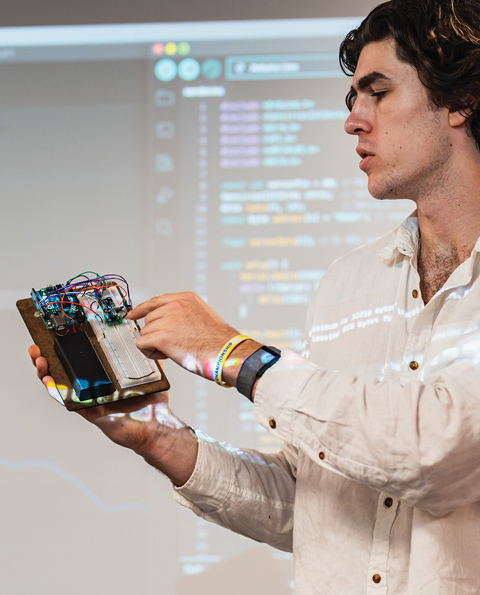 Kiran Kling ’24 demonstrates his prototype of a wearable sensor that measures methane output from cows in order to help small-scale farmers reduce their carbon footprint. Photo by Meka Wilson