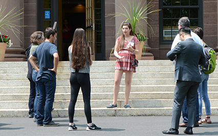 A student leads a group of people outside an astronomy building.