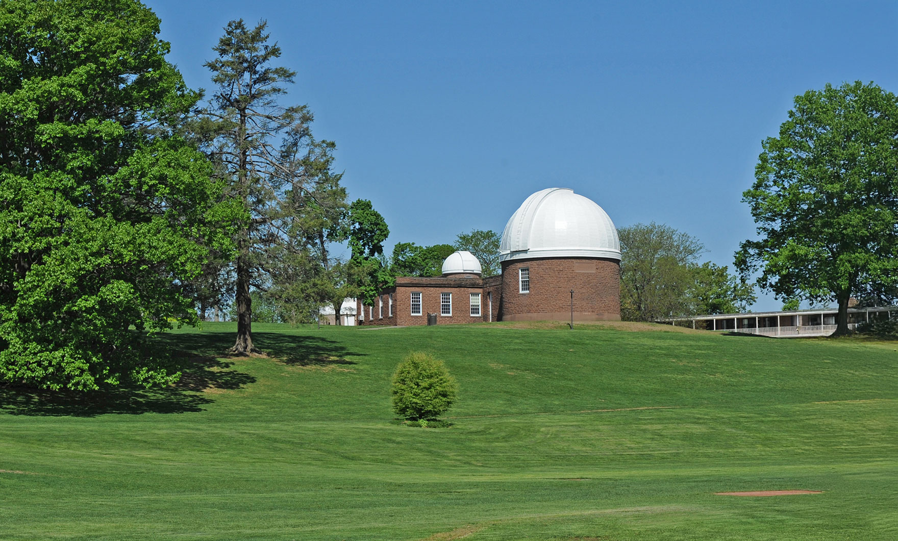 Wesleyan’s Van Vleck Observatory sits on a green lawn under a clear blue sky.